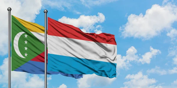 Bandera de Comoras y Luxemburgo ondeando en el viento contra el cielo azul nublado blanco juntos. Concepto diplomático, relaciones internacionales . — Foto de Stock