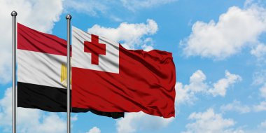 Mısır ve Tonga bayrağı birlikte beyaz bulutlu mavi gökyüzüne karşı rüzgarda sallayarak. Diplomasi kavramı, uluslararası ilişkiler.