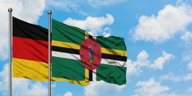 Almanya ve Dominika bayrağı birlikte beyaz bulutlu mavi gökyüzüne karşı rüzgarda sallayarak. Diplomasi kavramı, uluslararası ilişkiler.