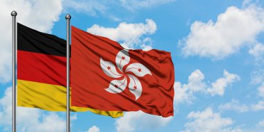 Almanya ve Hong Kong bayrağı birlikte beyaz bulutlu mavi gökyüzüne karşı rüzgarda sallayarak. Diplomasi kavramı, uluslararası ilişkiler.