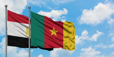 Mısır ve Kamerun bayrağı birlikte beyaz bulutlu mavi gökyüzüne karşı rüzgarsal sallayarak. Diplomasi kavramı, uluslararası ilişkiler.