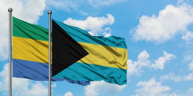 Gabon ve Bahamalar bayrağı birlikte beyaz bulutlu mavi gökyüzüne karşı rüzgarda sallayarak. Diplomasi kavramı, uluslararası ilişkiler.