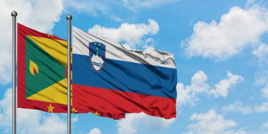 Grenada ve Slovenya bayrağı birlikte beyaz bulutlu mavi gökyüzüne karşı rüzgarda sallayarak. Diplomasi kavramı, uluslararası ilişkiler.