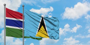 Gambiya ve Saint Lucia bayrağı birlikte beyaz bulutlu mavi gökyüzüne karşı rüzgarda sallayarak. Diplomasi kavramı, uluslararası ilişkiler.