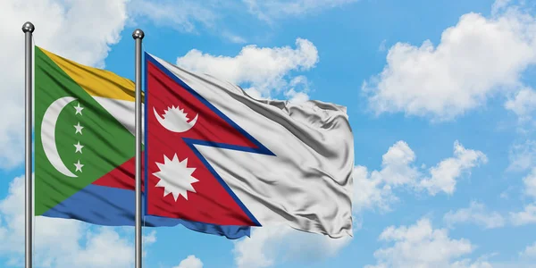 Bandera de las Comoras y Nepal ondeando en el viento contra el cielo azul nublado blanco juntos. Concepto diplomático, relaciones internacionales . — Foto de Stock