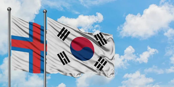 Bandera de las Islas Feroe y Corea del Sur ondeando en el viento contra el cielo azul nublado blanco juntos. Concepto diplomático, relaciones internacionales . —  Fotos de Stock