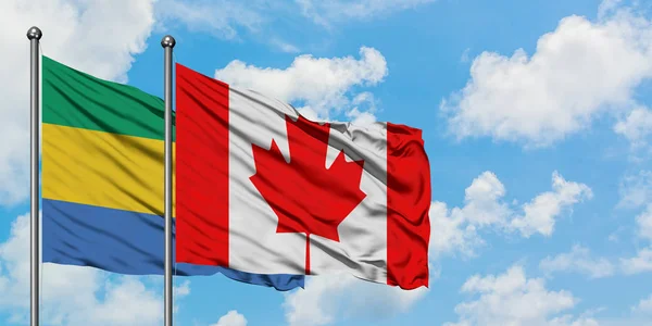 Gabón y la bandera de Canadá ondeando en el viento contra el cielo azul nublado blanco juntos. Concepto diplomático, relaciones internacionales . — Foto de Stock