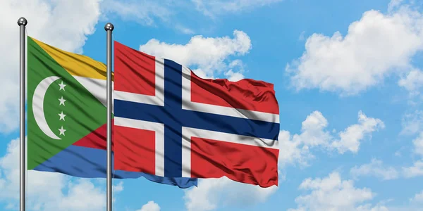 Bandera de las Comoras y Noruega ondeando en el viento contra el cielo azul nublado blanco juntos. Concepto diplomático, relaciones internacionales . — Foto de Stock