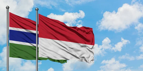 Bandera de Gambia y Mónaco ondeando en el viento contra el cielo azul nublado blanco juntos. Concepto diplomático, relaciones internacionales . — Foto de Stock