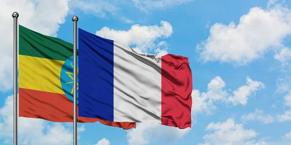 Bandera de Etiopía y Francia ondeando en el viento contra el cielo azul nublado blanco juntos. Concepto diplomático, relaciones internacionales . — Foto de Stock