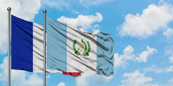 Fransa ve Guatemala bayrağı birlikte beyaz bulutlu mavi gökyüzüne karşı rüzgarda sallayarak. Diplomasi kavramı, uluslararası ilişkiler. — Stok fotoğraf