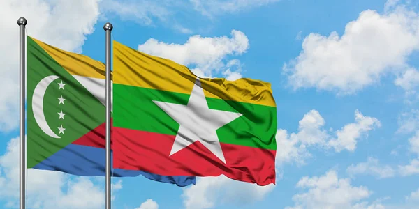 Bandera de las Comoras y Myanmar ondeando en el viento contra el cielo azul nublado blanco juntos. Concepto diplomático, relaciones internacionales . — Foto de Stock