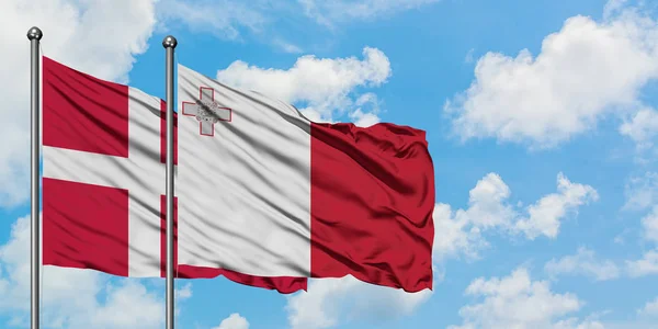 Dánsko a Malta vlají ve větru proti bíle zatažené modré obloze. Diplomacie, mezinárodní vztahy. — Stock fotografie