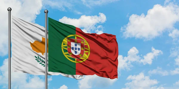 Zypern und die portugiesische Flagge wehen gemeinsam im Wind vor dem wolkenverhangenen blauen Himmel. Diplomatie-Konzept, internationale Beziehungen. — Stockfoto