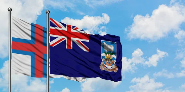 Faeröer eilanden en Falklandeilanden vlag zwaaien in de wind tegen witte bewolkte blauwe hemel samen. Diplomatie concept, internationale betrekkingen. — Stockfoto