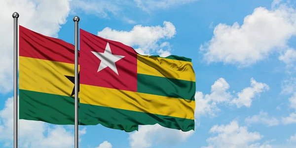 Bandera de Ghana y Togo ondeando en el viento contra el cielo azul nublado blanco juntos. Concepto diplomático, relaciones internacionales . — Foto de Stock