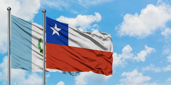 Guatemale a Chilská vlajka mávali ve větru proti bíle zatažené modré obloze. Diplomacie, mezinárodní vztahy. — Stock fotografie