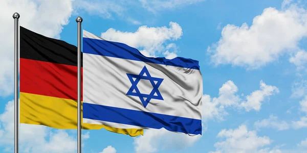 Germany and Israel flag waving in the wind against white cloudy blue sky together. Diplomacy concept, international relations.