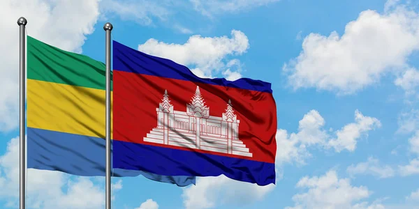 Gabon och Kambodja flagga vinka i vinden mot vit grumlig blå himmel tillsammans. Diplomatisk koncept, internationella relationer. — Stockfoto