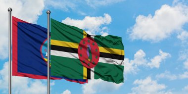 Guam ve Dominika bayrağı birlikte beyaz bulutlu mavi gökyüzüne karşı rüzgarda sallayarak. Diplomasi kavramı, uluslararası ilişkiler.