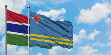 Gambiya ve Aruba bayrağı birlikte beyaz bulutlu mavi gökyüzüne karşı rüzgarda sallayarak. Diplomasi kavramı, uluslararası ilişkiler.