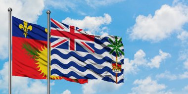 Guadeloupe ve İngiliz Hint Okyanusu Toprakları bayrağı birlikte beyaz bulutlu mavi gökyüzüne karşı rüzgarda sallayarak. Diplomasi kavramı, uluslararası ilişkiler.