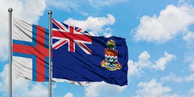 Faroe Adaları ve Cayman Adaları bayrak birlikte beyaz bulutlu mavi gökyüzüne karşı rüzgarda sallayarak. Diplomasi kavramı, uluslararası ilişkiler.