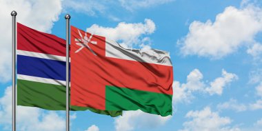 Gambiya ve Umman bayrağı birlikte beyaz bulutlu mavi gökyüzüne karşı rüzgarda sallayarak. Diplomasi kavramı, uluslararası ilişkiler.