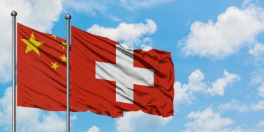 Çin ve İsviçre bayrağı birlikte beyaz bulutlu mavi gökyüzüne karşı rüzgarsal sallayarak. Diplomasi kavramı, uluslararası ilişkiler.