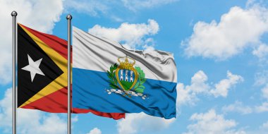 Doğu Timor ve San Marino bayrağı birlikte beyaz bulutlu mavi gökyüzüne karşı rüzgarda sallayarak. Diplomasi kavramı, uluslararası ilişkiler.