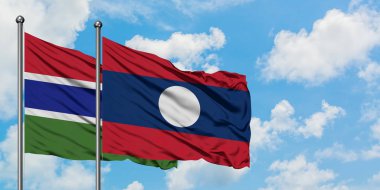 Gambiya ve Laos bayrağı birlikte beyaz bulutlu mavi gökyüzüne karşı rüzgarda sallayarak. Diplomasi kavramı, uluslararası ilişkiler.