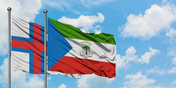 Bandera de las Islas Feroe y Guinea Ecuatorial ondeando en el viento contra el cielo azul nublado blanco juntos. Concepto diplomático, relaciones internacionales . — Foto de Stock