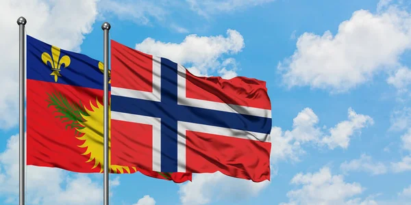 Bandera de Guadalupe y Bouvet Islands ondeando en el viento contra el cielo azul nublado blanco juntos. Concepto diplomático, relaciones internacionales . — Foto de Stock