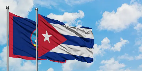 Bandera de Guam y Cuba ondeando en el viento contra el cielo azul nublado blanco juntos. Concepto diplomático, relaciones internacionales . — Foto de Stock