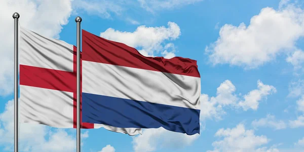 Bandera de Inglaterra y Holanda ondeando en el viento contra el cielo azul nublado blanco juntos. Concepto diplomático, relaciones internacionales . —  Fotos de Stock