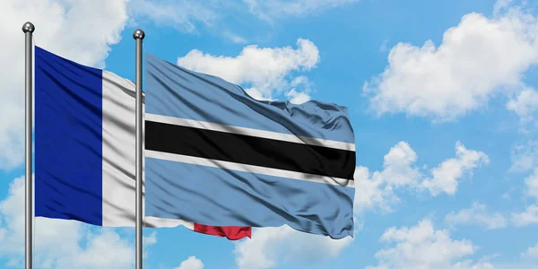 Francia e Botswana sventolano nel vento contro il bianco cielo azzurro nuvoloso insieme. Concetto di diplomazia, relazioni internazionali . — Foto Stock