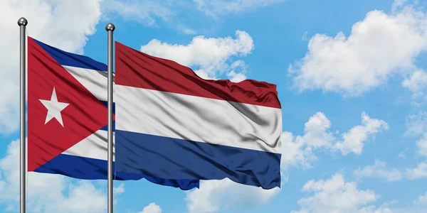 Bandera de Cuba y Holanda ondeando en el viento contra el cielo azul nublado blanco juntos. Concepto diplomático, relaciones internacionales . — Foto de Stock