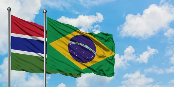 Bandera de Gambia y Brasil ondeando en el viento contra el cielo azul nublado blanco juntos. Concepto diplomático, relaciones internacionales . — Foto de Stock