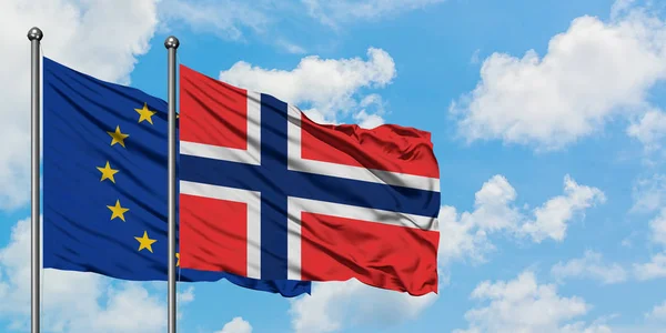Bandera de la Unión Europea y las Islas Bouvet ondeando en el viento contra el cielo azul nublado blanco juntos. Concepto diplomático, relaciones internacionales . — Foto de Stock