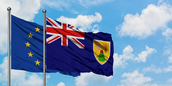 Bandera de la Unión Europea y las Islas Turcas y Caicos ondeando en el viento contra el cielo azul nublado blanco juntos. Concepto diplomático, relaciones internacionales . — Foto de Stock
