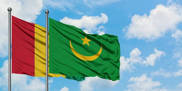 Bandera de Guinea y Mauritania ondeando en el viento contra el cielo azul nublado blanco juntos. Concepto diplomático, relaciones internacionales . — Foto de Stock