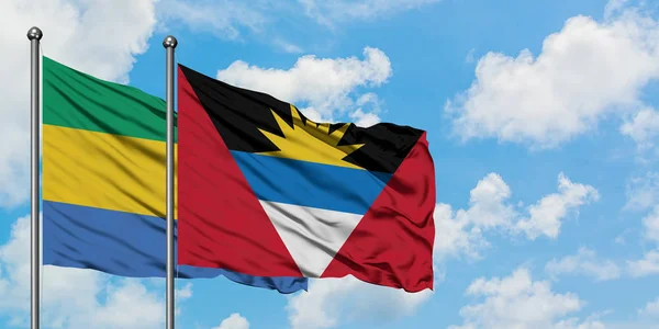 Gabon ve Antigua ve Barbuda bayrağı birlikte beyaz bulutlu mavi gökyüzüne karşı rüzgarda sallayarak. Diplomasi kavramı, uluslararası ilişkiler. — Stok fotoğraf