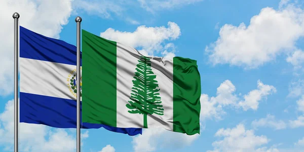 El Salvador i Wyspa Norfolk flaga machając w wiatr przed białym zachmurzone błękitne niebo razem. Koncepcja dyplomacji, stosunki międzynarodowe. — Zdjęcie stockowe