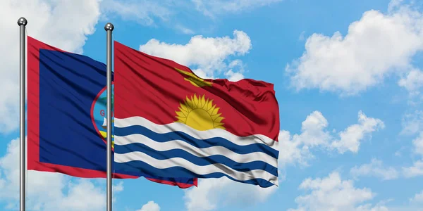 Bandera de Guam y Kiribati ondeando en el viento contra el cielo azul nublado blanco juntos. Concepto diplomático, relaciones internacionales . — Foto de Stock