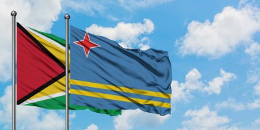 Guyana ve Aruba bayrağı birlikte beyaz bulutlu mavi gökyüzüne karşı rüzgarda sallayarak. Diplomasi kavramı, uluslararası ilişkiler.