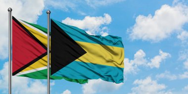 Guyana ve Bahamalar bayrağı birlikte beyaz bulutlu mavi gökyüzüne karşı rüzgarda sallayarak. Diplomasi kavramı, uluslararası ilişkiler.