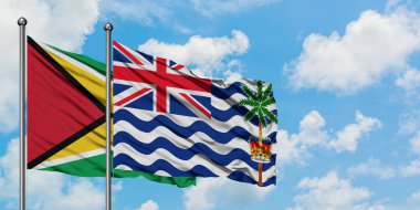 Guyana ve İngiliz Hint Okyanusu Toprakları bayrağı birlikte beyaz bulutlu mavi gökyüzüne karşı rüzgarda sallayarak. Diplomasi kavramı, uluslararası ilişkiler.