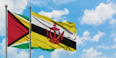 Guyana ve Brunei bayrağı birlikte beyaz bulutlu mavi gökyüzüne karşı rüzgarda sallayarak. Diplomasi kavramı, uluslararası ilişkiler.