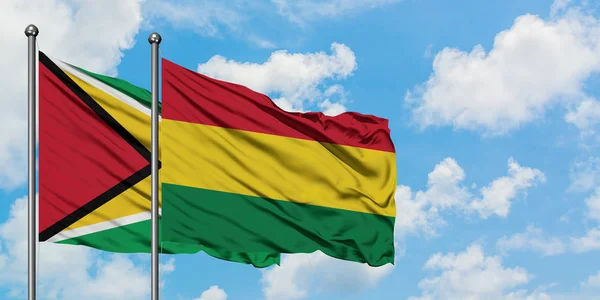 Guyana e Bolivia bandiera sventolando nel vento contro bianco cielo blu nuvoloso insieme. Concetto di diplomazia, relazioni internazionali . — Foto Stock