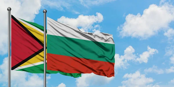 Bandera de Guyana y Bulgaria ondeando en el viento contra el cielo azul nublado blanco juntos. Concepto diplomático, relaciones internacionales . — Foto de Stock